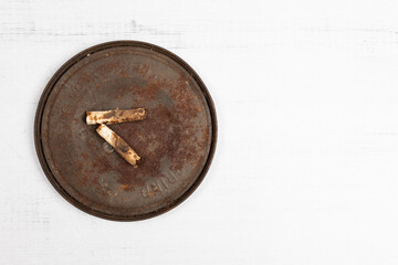 Two old cigarette buts on a rusty lid