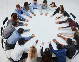 a group of young people sitting at a round table with their arms outstretched