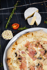 Bacon Pizza. Italian Carbonara Pizza with bacon and mozzarella cheese on black table, top view, close up.