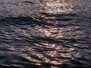 Sea glittering water waves at sunset.