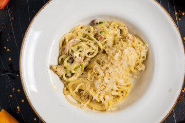 Tasty appetizing pasta spaghetti with pesto sauce and shrimps served in bowl on dark background. Top View with Copy Space.