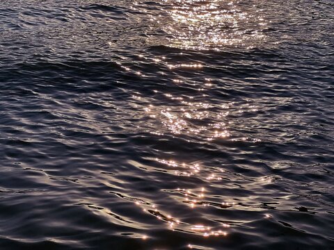 Sea glittering water waves at sunset.