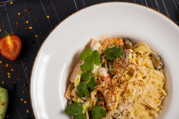 Tasty appetizing pasta spaghetti with pesto sauce and shrimps served in bowl on dark background. Top View with Copy Space.