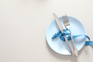 fork and knife with measuring tape on white background 