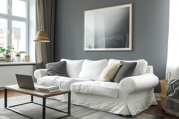 gray walls, a white sofa and chair, a laptop on a coffee table, and a horizontal poster can all be seen in this side view of a living room.