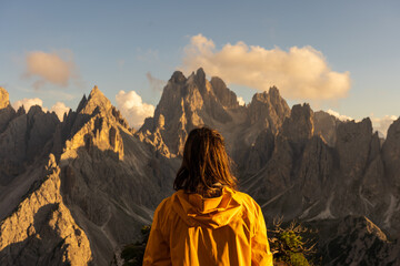 woman from behind observing majestic dolomite mountains at sunset