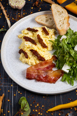 Breakfast with scrambled eggs, bacon and vegetable salad