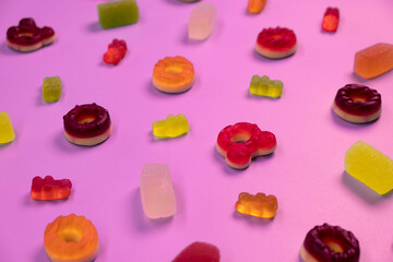 pink background of various jelly sweets, bears, donuts, candies, on pink background close-up top view concept birthday party or celebration 