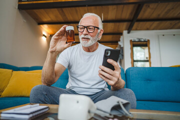 senior man sit at home hold bottle medicine pills drugs and smartphone
