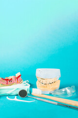 Fototapeta na wymiar Close up of tooth model, brushes, floss and dental tools on teal background.