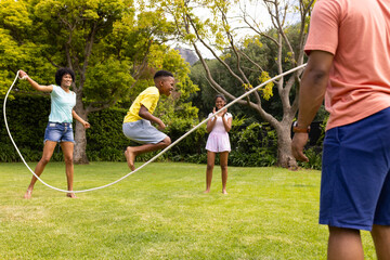 An African American family enjoys a sunny day playing with a jump rope outdoors
