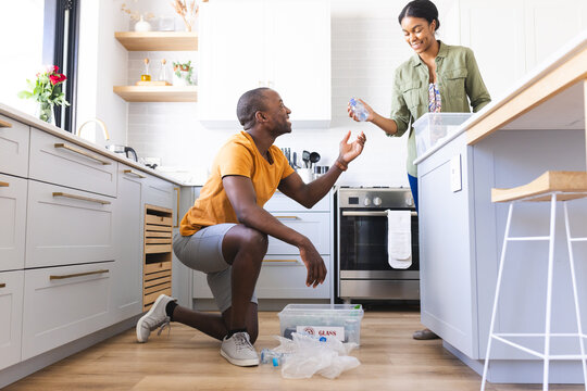 A diverse couple is in kitchen recycling at home - Powered by Adobe