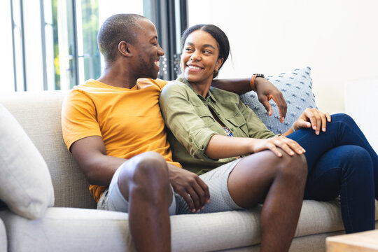 A young African American couple relaxes on a sofa, sharing a moment at home