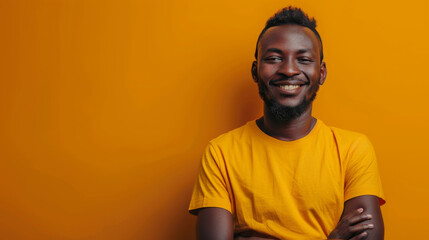 Portrait of a joyful African man smiling broadly, wearing a yellow shirt against an orange background. - obrazy, fototapety, plakaty