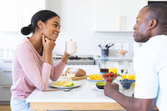 A diverse couple enjoys breakfast in a bright kitchen at home