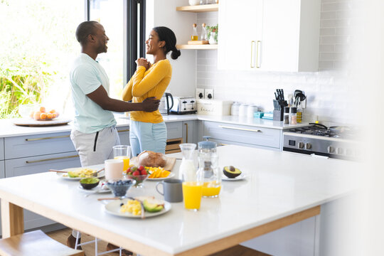 A diverse couple shares a moment in a sunlit kitchen at home at breakfast