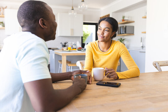 African American couple enjoys a conversation over coffee at home in the kitchen