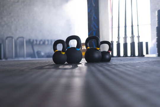 Kettlebells are lined up on a gym floor with copy space