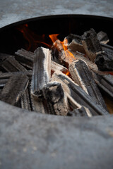 Round barbecue with burning wood and coal. Fire in the grill fire close-up.	
