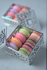 Artificial mini-French macarons with various colors on silver container isolated on white.