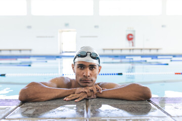 A fit young Caucasian male athlete swimmer rests at the pool's edge