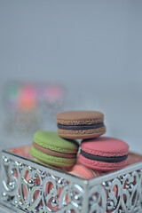 Artificial mini-French macarons with various colors on silver container isolated on white.