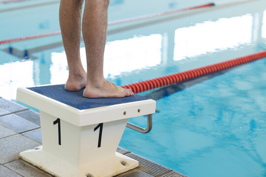 A person stands poised on a diving block, labeled with the number one, with copy space