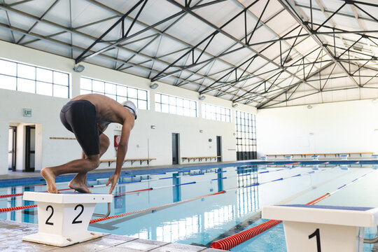 A young African American male athlete swimmer prepares to dive into a pool with copy space