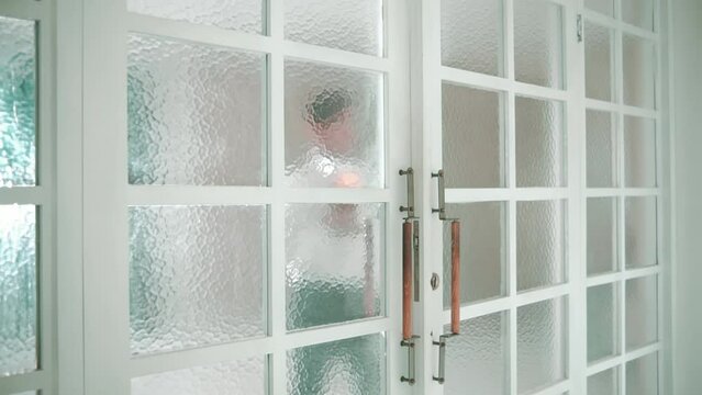 Man seen through textured glass door in a modern home interior.
