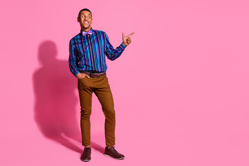Full length photo of dreamy good mood guy dressed striped shirt looking pointing finger empty space isolated pink color background