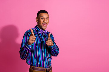 Photo of funky cool guy wear striped shirt pointing fingers you empty space isolated pink color background