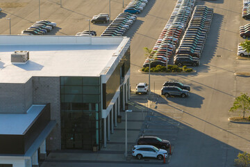 Aerial view of dealership parking lot with many brand new cars for sale. Development of american...