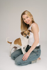Happy two friends. Blonde pretty woman and her cute pet dog Jack Russell terrier. Studio shot. Grey background