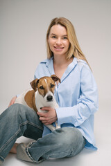 Blonde Woman and dog Jack Russell terrier studio portrait. Cute friends. Gray background