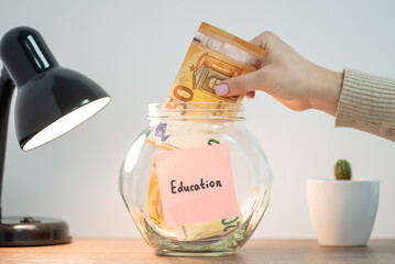 Saving money for education concept. Female putting euro money to jar with inscription Education