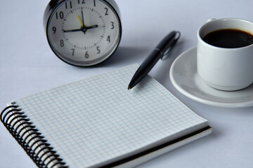 Close-up of a blank notepad with a black pen and a cup of coffee on a white background.