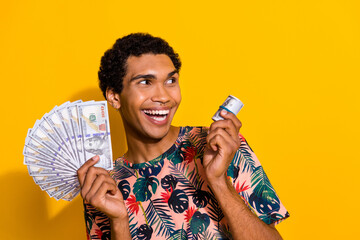 Photo of wealthy young guy tourist holding banknotes advertising and looking betting company...