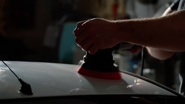 A man polishes a car with a polishing machine