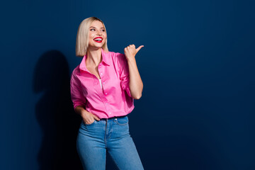 Fototapeta premium Photo of nice positive woman with bob hairstyle dressed pink shirt look directing at sale empty space isolated on dark blue background