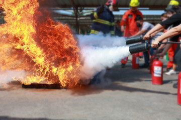 Employees firefighting training, Concept Employees hand using fire extinguisher fighting fire...