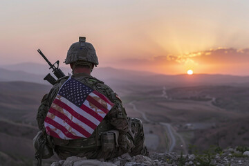 A soldier with an American flag sits admiring the sunset and remembers the dead - obrazy, fototapety, plakaty