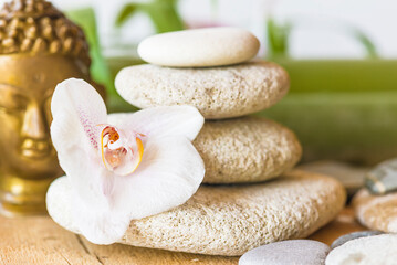 White orchid flower, pyramide of pebbles and buddha statue; Zen-like concept