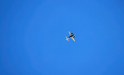 Ground-based photograph of a twin-engine plane under a blue sky.