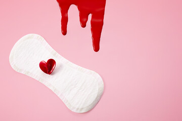 Blood, feminine hygiene pad with red heart on pink background. First menstrual period concept,...
