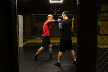 Obraz premium Two professional boxer boxing in dark gym. Boxer training concept.