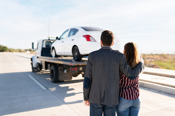 Man and young women hugging as they see their car being towed
