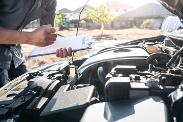 Technician engineer working of car mechanic in doing checklist for repairs engine writing to the...