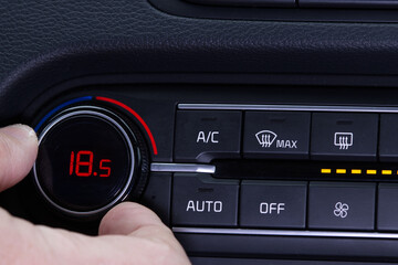 Set up air conditioner in the car. Hand turns air conditioner ring. Display indicates 18.5 degree...