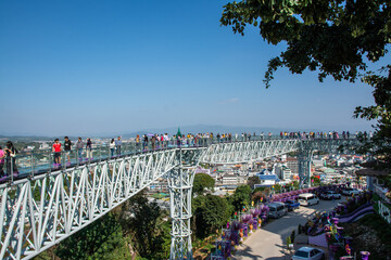 CHIANG RAI, THAILAND - December 23, 2023: Tourists take skywalk at Wat Phra That Doi Wao at the border of Thailand and Myanmar. - obrazy, fototapety, plakaty