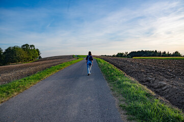 Silhouettes of a woman, a lonely man himself in the middle of the road among the fields
